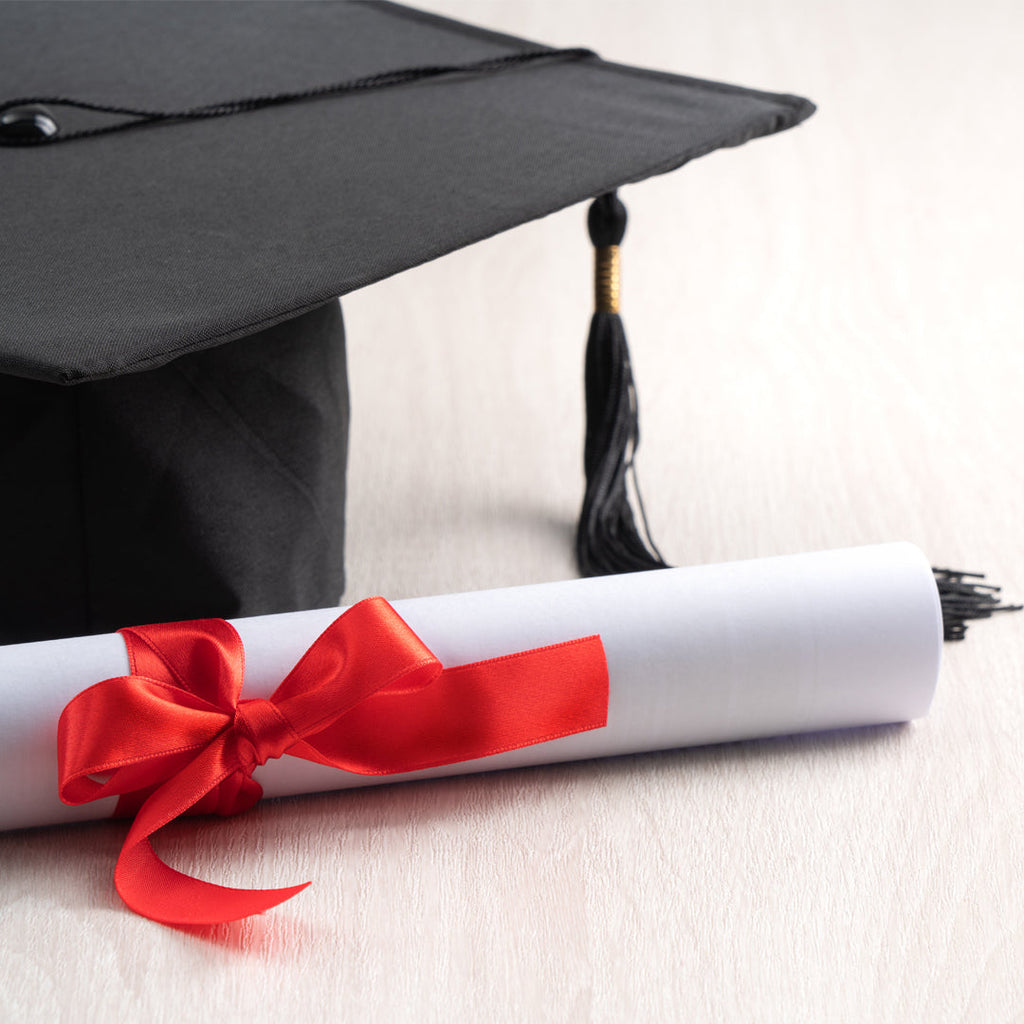 Cap with tassel and a diploma with red ribbon.
