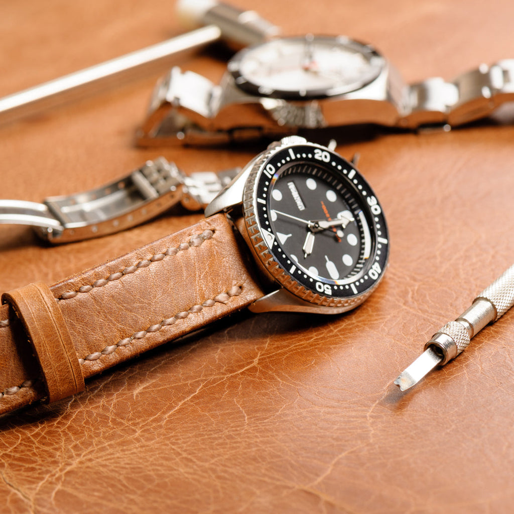two watches with a leather band and a stainless steel bracelet.