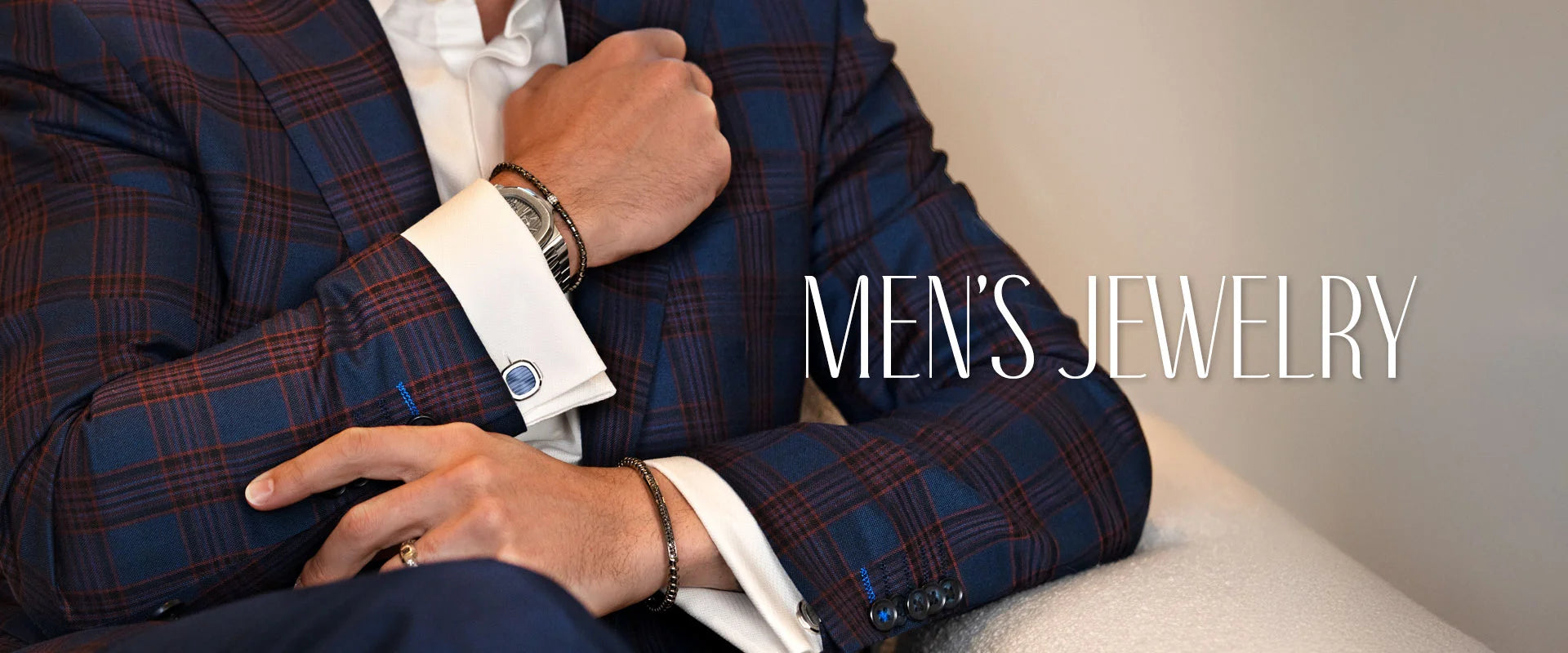 Man wearing a yellow gold ring leaning on a wall in a suit