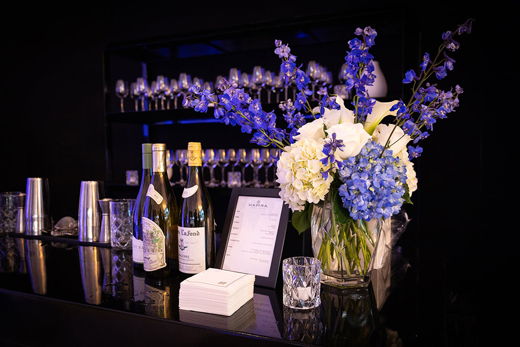 Image of a bar top with flowers, bottles and a menu