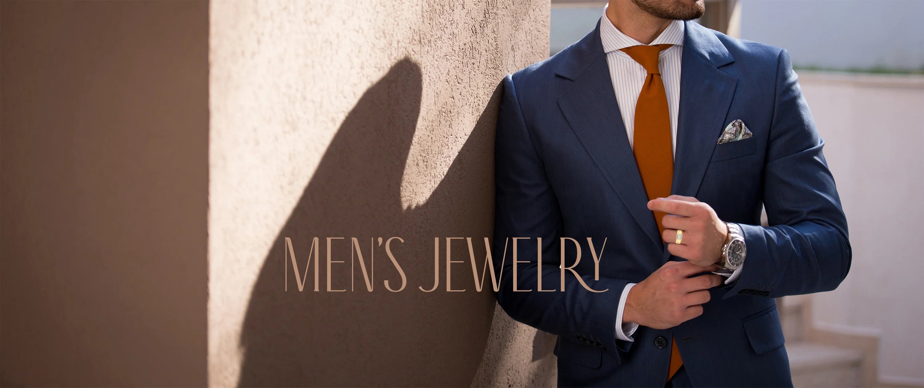 Man wearing a yellow gold ring leaning on a wall in a suit